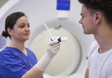 Eine medizinische Technologin für Radiologie reicht einem Patienten den Contrast Booster von ulrich medical für ein Lungenembolie-CT Untersuchung an. | © 2025 ulrich medical. Alle Rechte vorbehalten. Die Verwendung, Vervielfältigung oder Weitergabe ohne ausdrückliche Genehmigung ist nicht gestattet.
