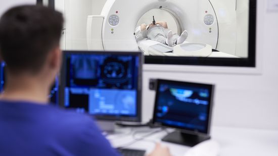 Sicht aus dem Kontrollraum in den Untersuchungsraum auf einem Patienten, bei dem ein Lungenembolie-CT mit dem Contrast Booster im Mund gemacht wird. | © 2025 ulrich medical. Alle Rechte vorbehalten. Die Verwendung, Vervielfältigung oder Weitergabe ohne ausdrückliche Genehmigung ist nicht gestattet.